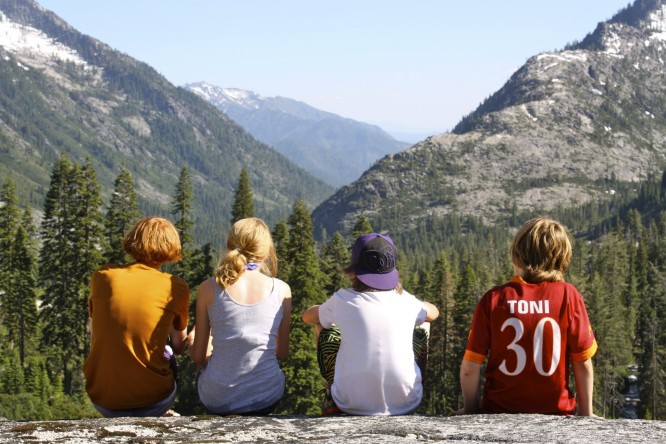 Four campers sit on a rock overlooking the Trinity Alps wilderness