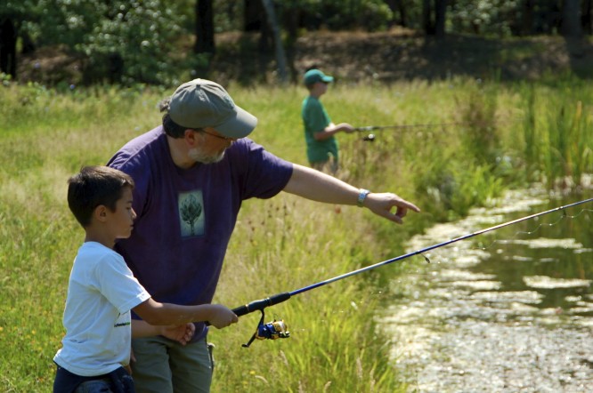Camp doctor instructs a camper to cast a fishing rod