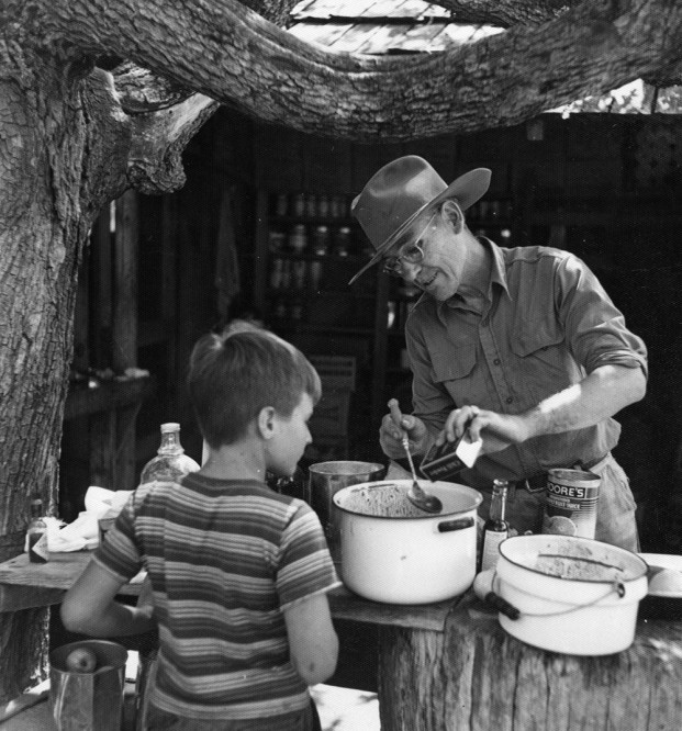 Grover Gates cooks for camper in front of Leedy Lodge