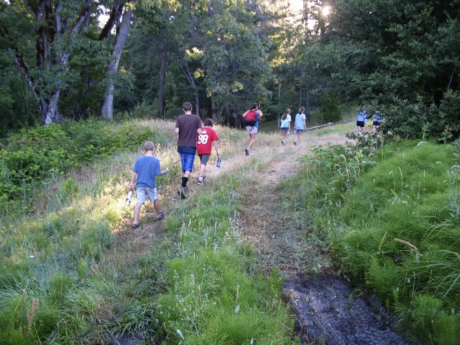 campers hiking down a grassy trail