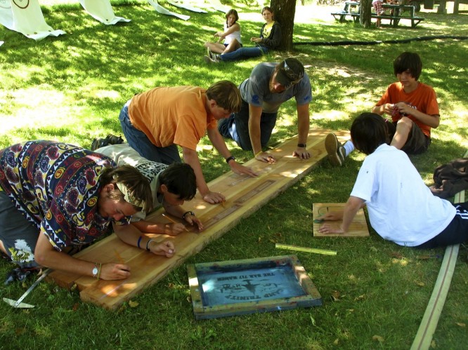 Campers work to design the words on the Wooden sign that will adorn the main gate of camp 