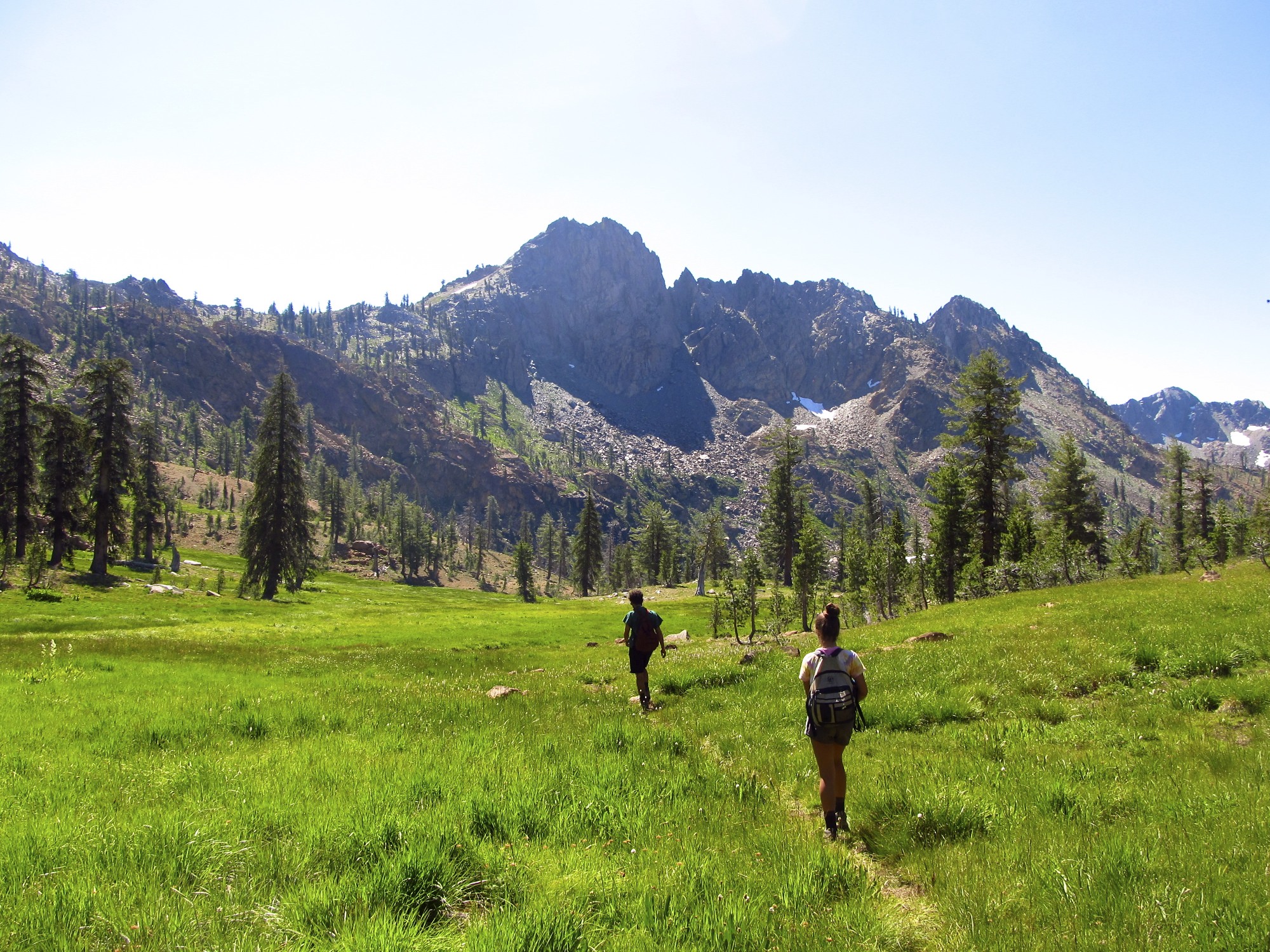 Campers wearing backpacks hike on a trail in the Trinity Alps