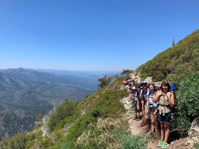 Campers with backpacks pose on trail in the Trinity Alps