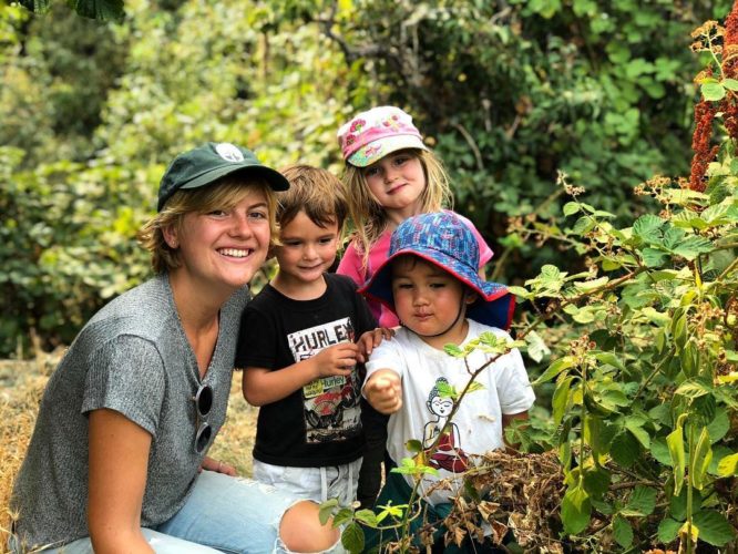 Counselor and three young children pick blackberries
